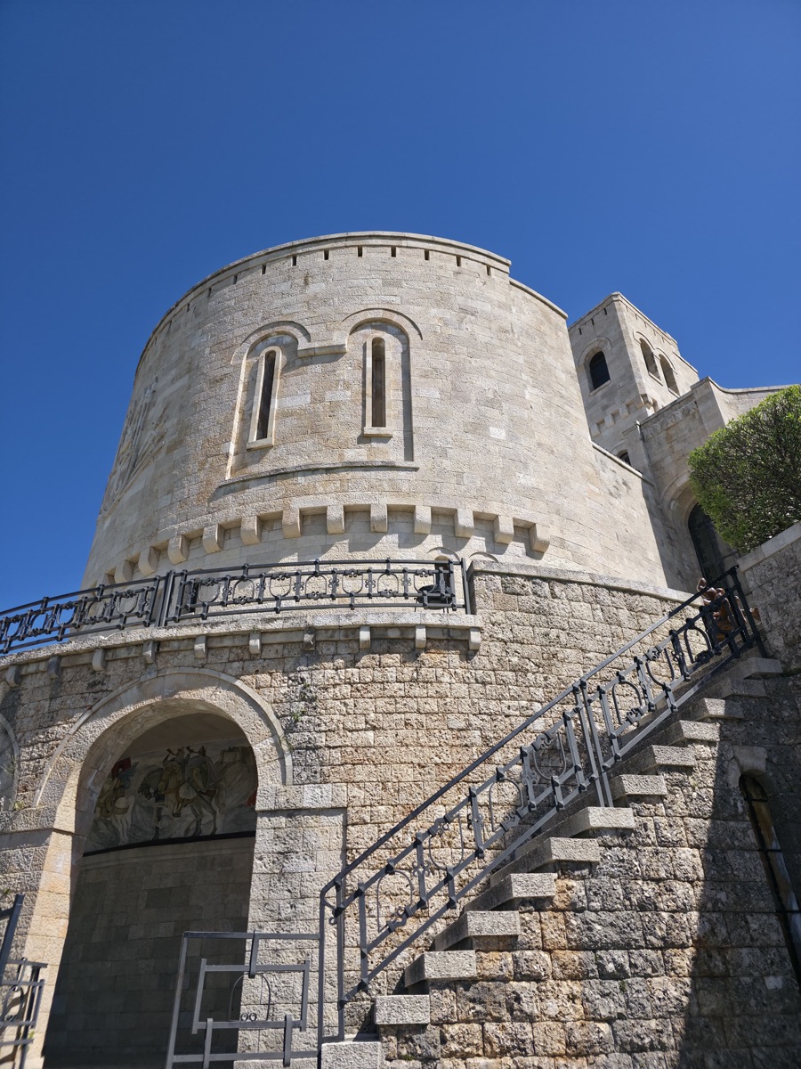 The round stone tower of Krujë Castle against a deep blue sky