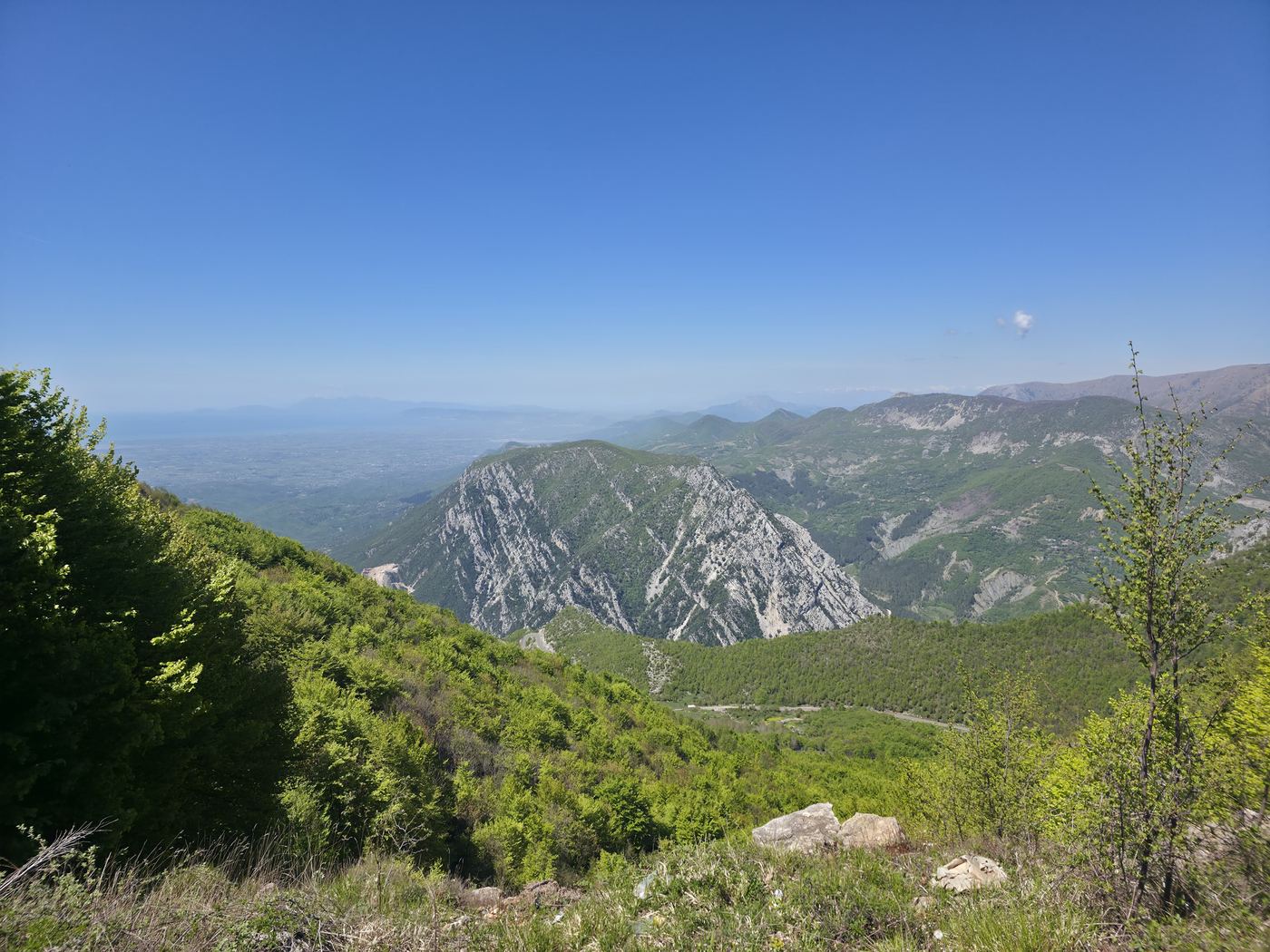 The limestone face of the mountain above Krujë, green ridges rolling down to the hazy Adriatic coast